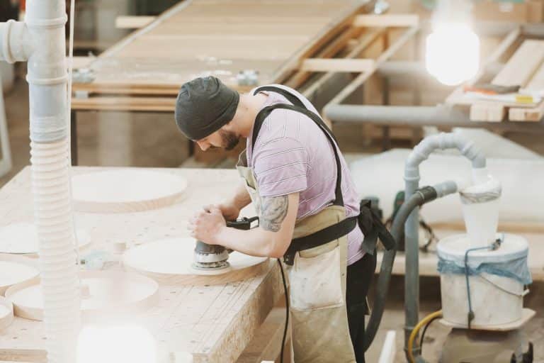 artisan utilisant une ponceuse excentrique pour poncer du bois
