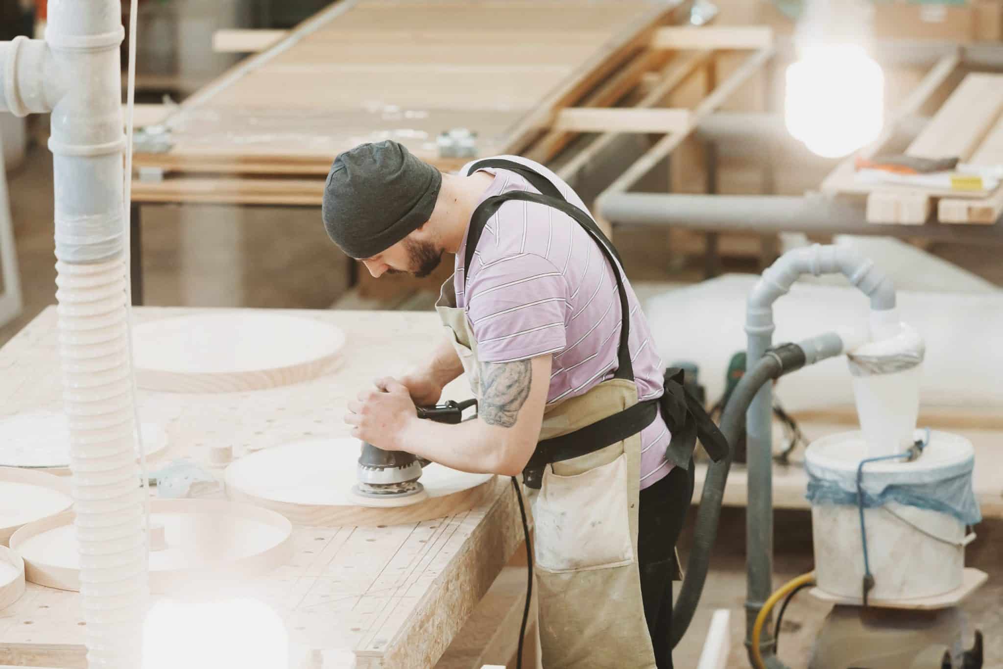artisan utilisant une ponceuse excentrique pour poncer du bois
