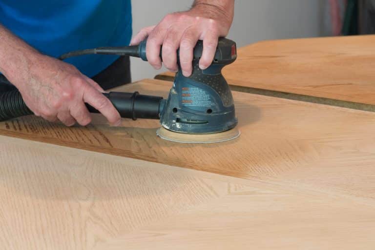 menuisier montrant comment on peut poncer une table en bois