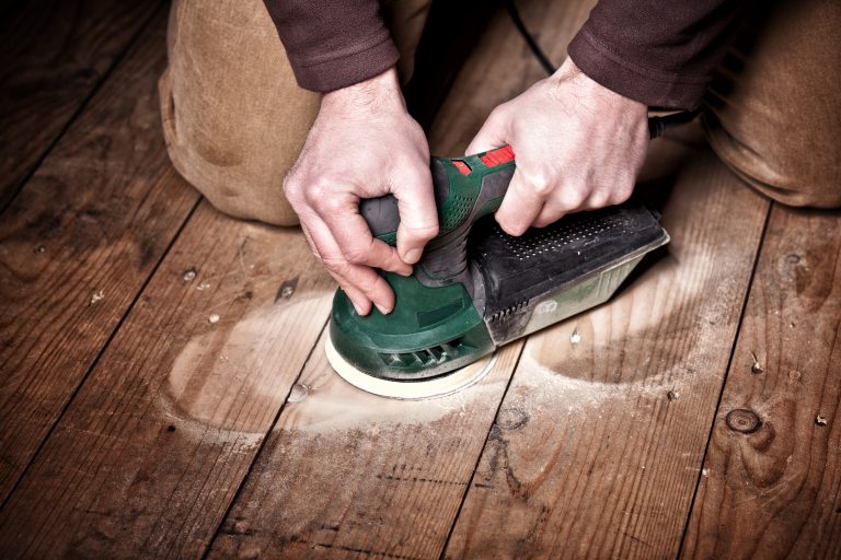 homme utilisant une ponceuse excentrique pour son parquet