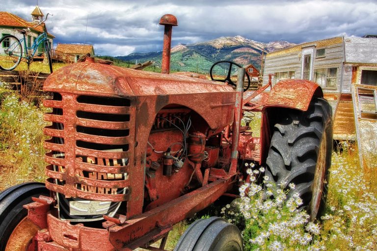 un agriculteur cherchant à comprendre comment poncer un tracteur et le repeindre plus tard