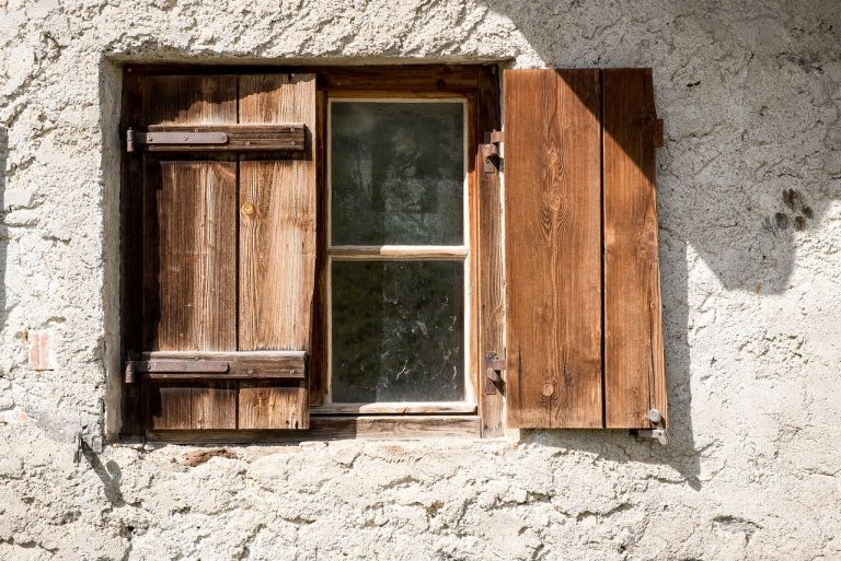 un propriétaire de maison demandant à un artisan les étapes sur comment poncer un volet en bois abimé par le vent