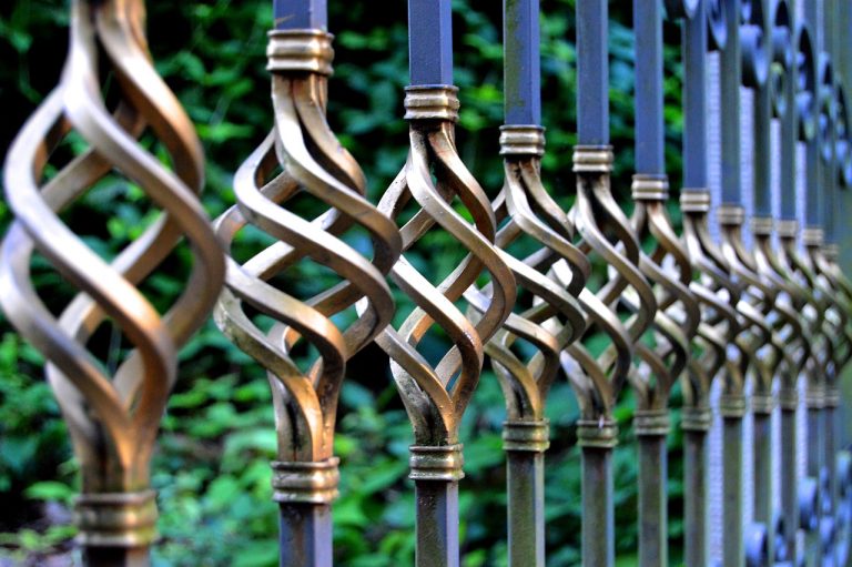 un bricoleur avec une porte de fer forgée se demandant comment rénover un garde corps en fer